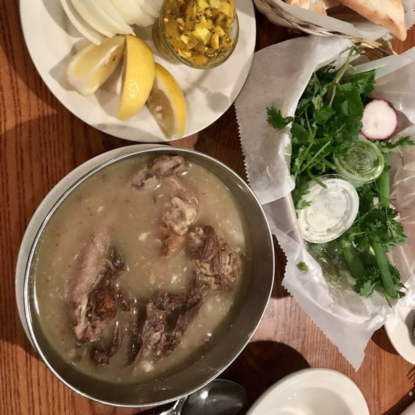 A Persian dish of meat and broth, with sides of lemon, onions, herbs, and bread.